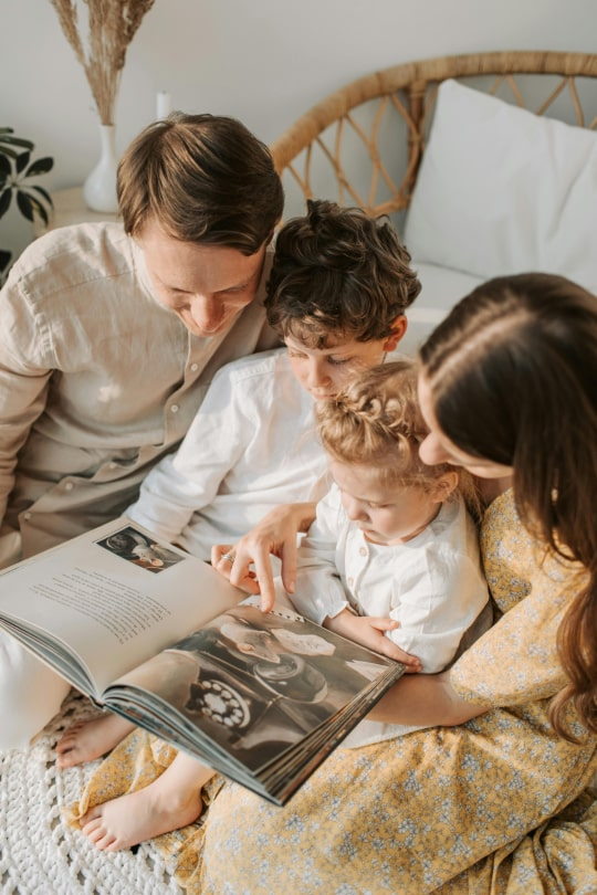 Famille feuilletant un album, illustrant la vision Bercail